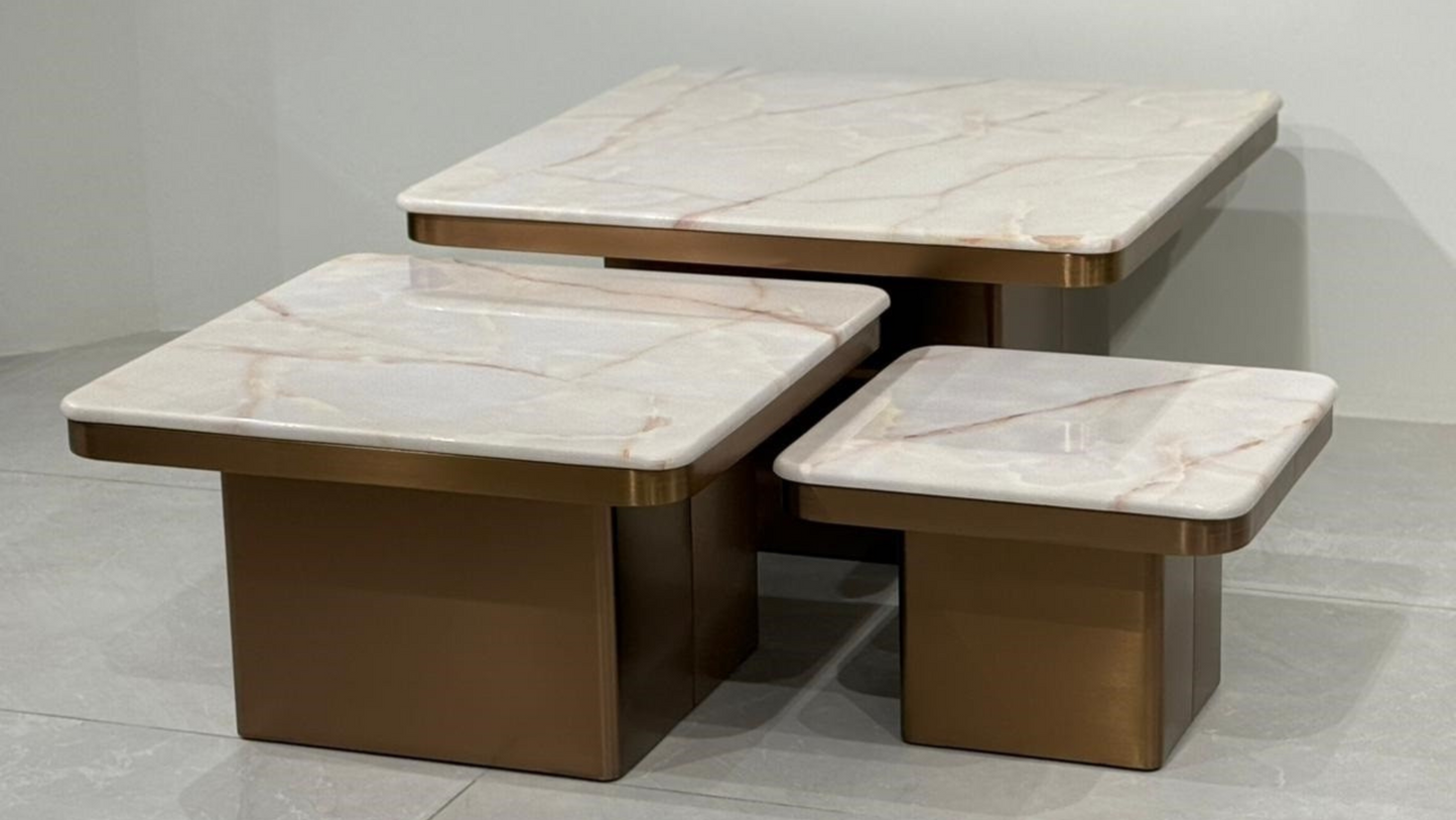 Luxury rose gold square center table trio with soft beige marble tops in a tiered nesting layout