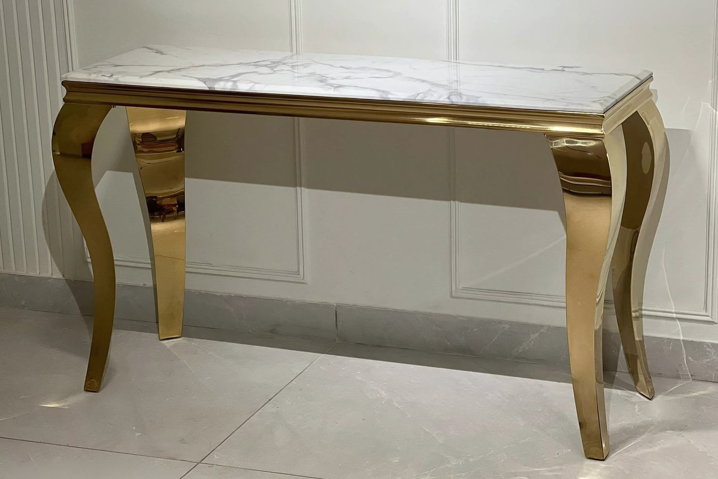 A black marble console table with gold looped legs, displayed against a neutral background.