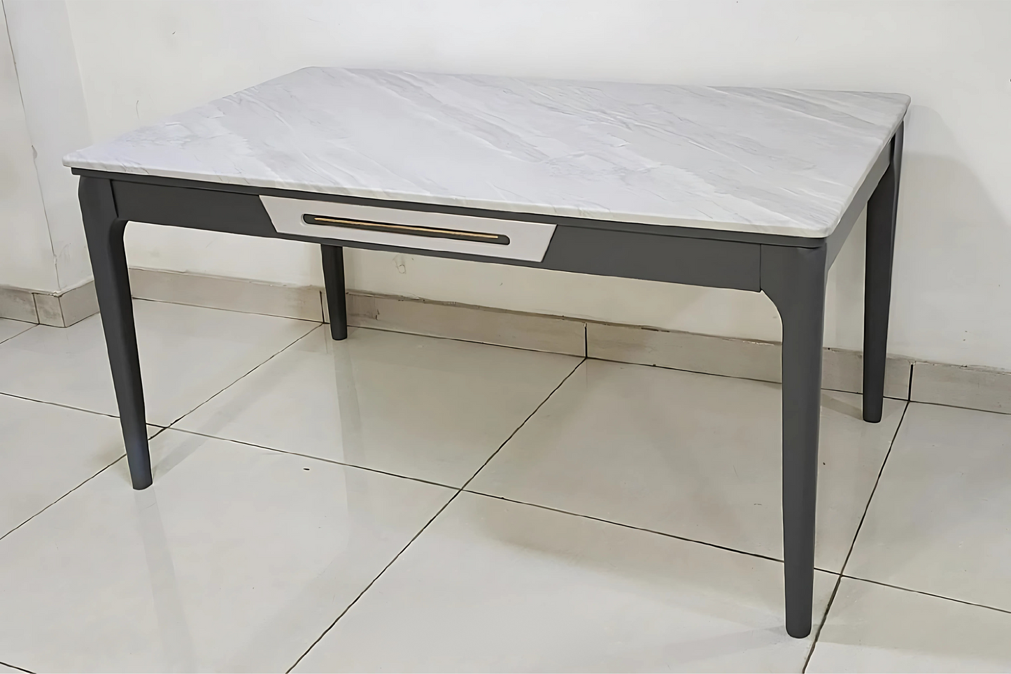 Contemporary dining table with white marble-finish top and graphite frame featuring gold-accented drawer detail