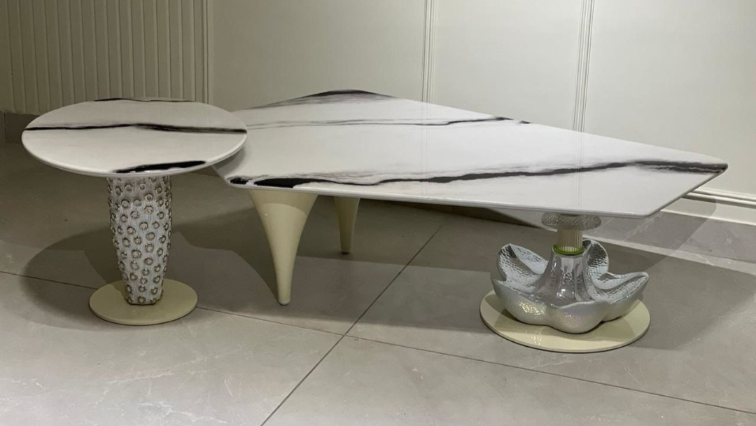 Artistic marble-pattern center coffee table with sculptural mixed-material legs in a luxury setting