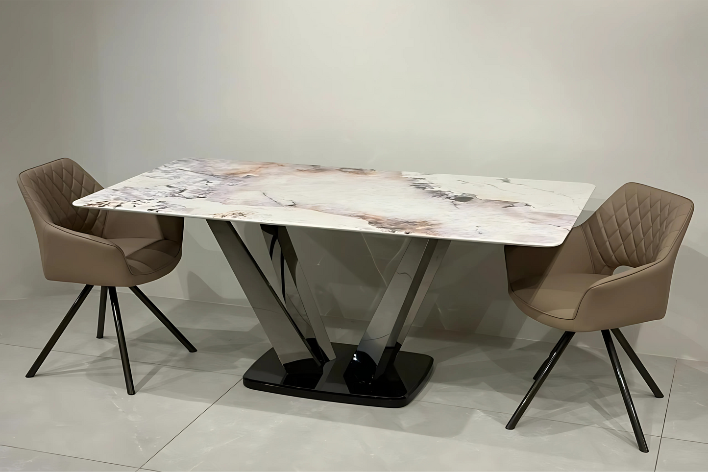 Luxury marble dining table with V-shaped chrome base and taupe quilted chairs in modern contemporary style.