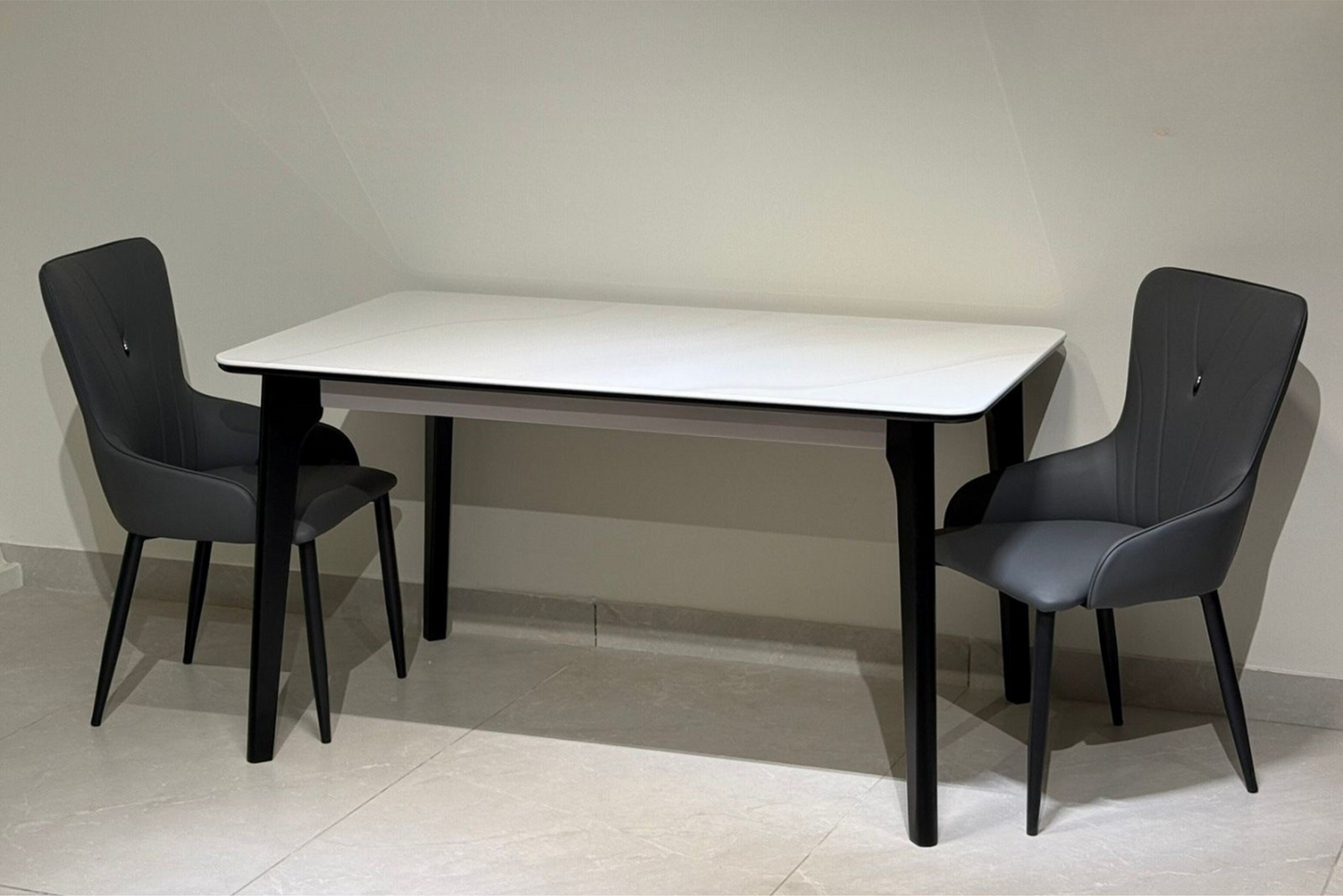 Minimalist white dining table with black legs and grey modern chairs in a clean interior