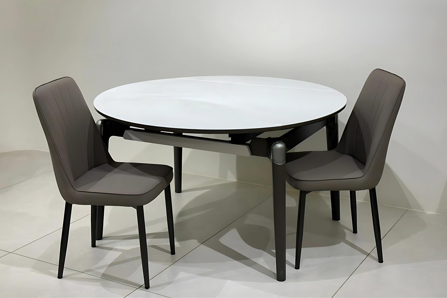Round white ceramic dining table with black frame and taupe stitched dining chairs in modern minimalist style.