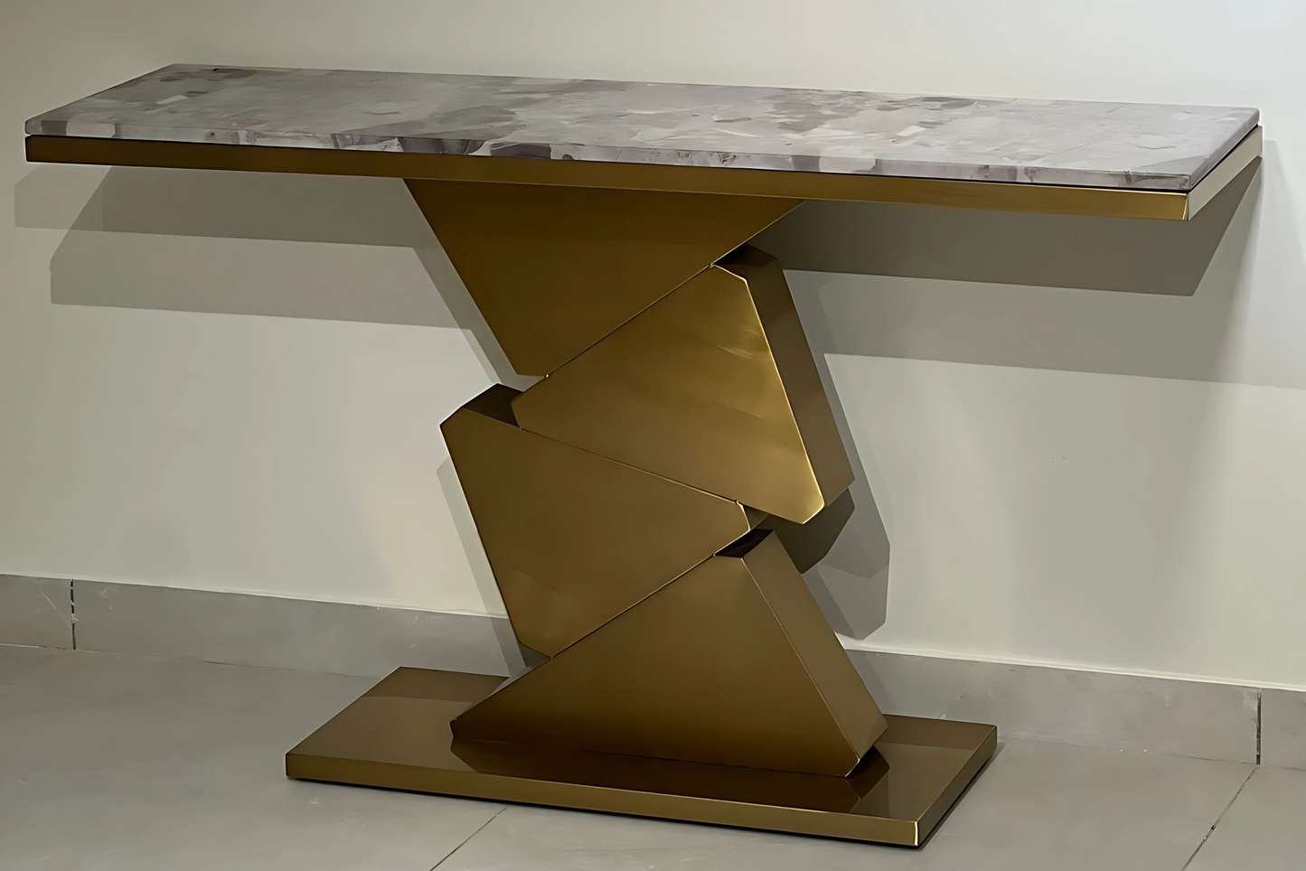 A black marble console table with gold looped legs positioned against a plain background.