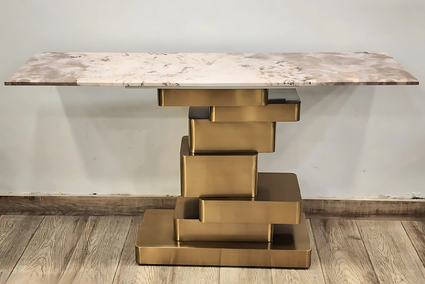 A black marble console table with gold looped legs on a wooden floor against a white background.