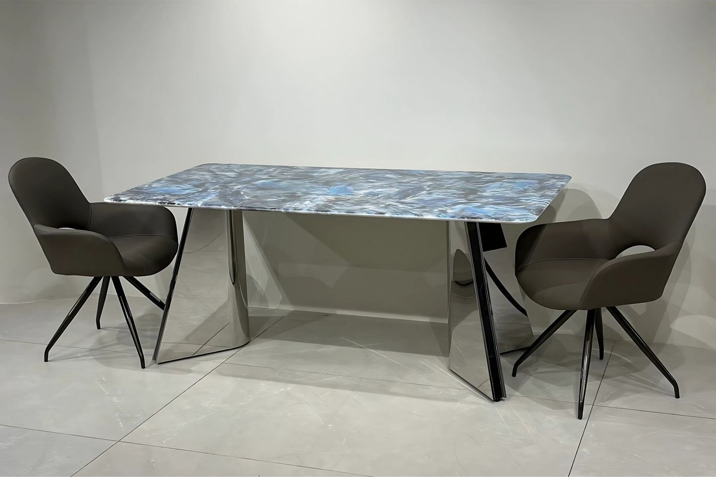 Blue-grey marble dining table with mirrored chrome legs and charcoal swivel dining chairs in modern luxury style.