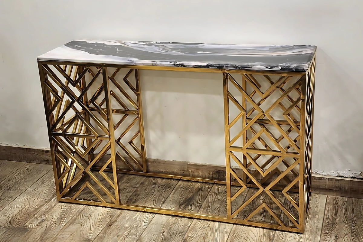 A black marble top console table with gold looped legs placed against a wall on a wooden floor.