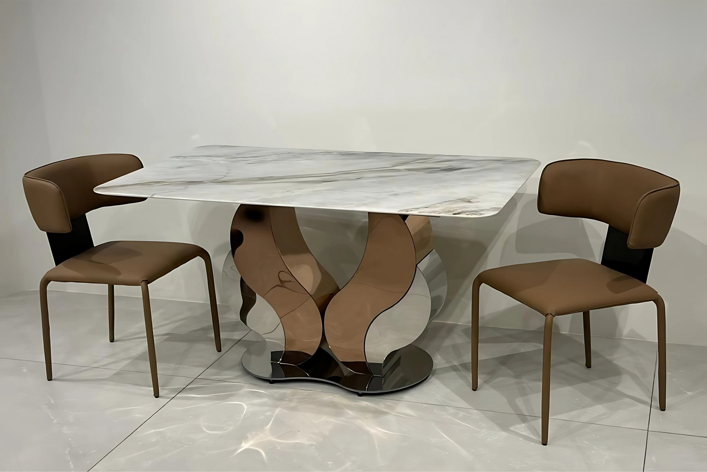 Marble dining table with sculptural mirrored base and two caramel designer chairs in artistic luxury style.