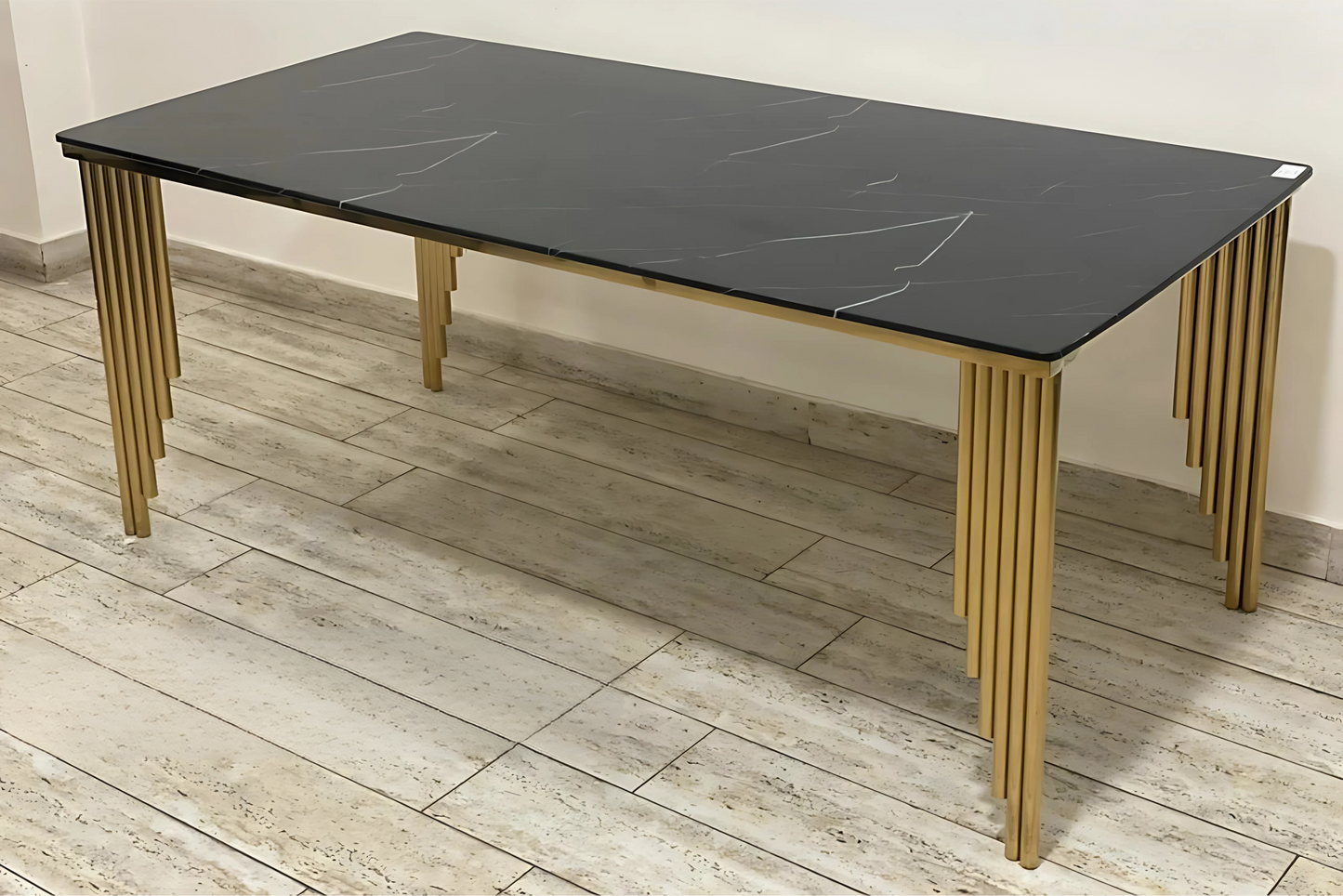 Black marble dining table with sculptural gold rod legs in a luxury modern design