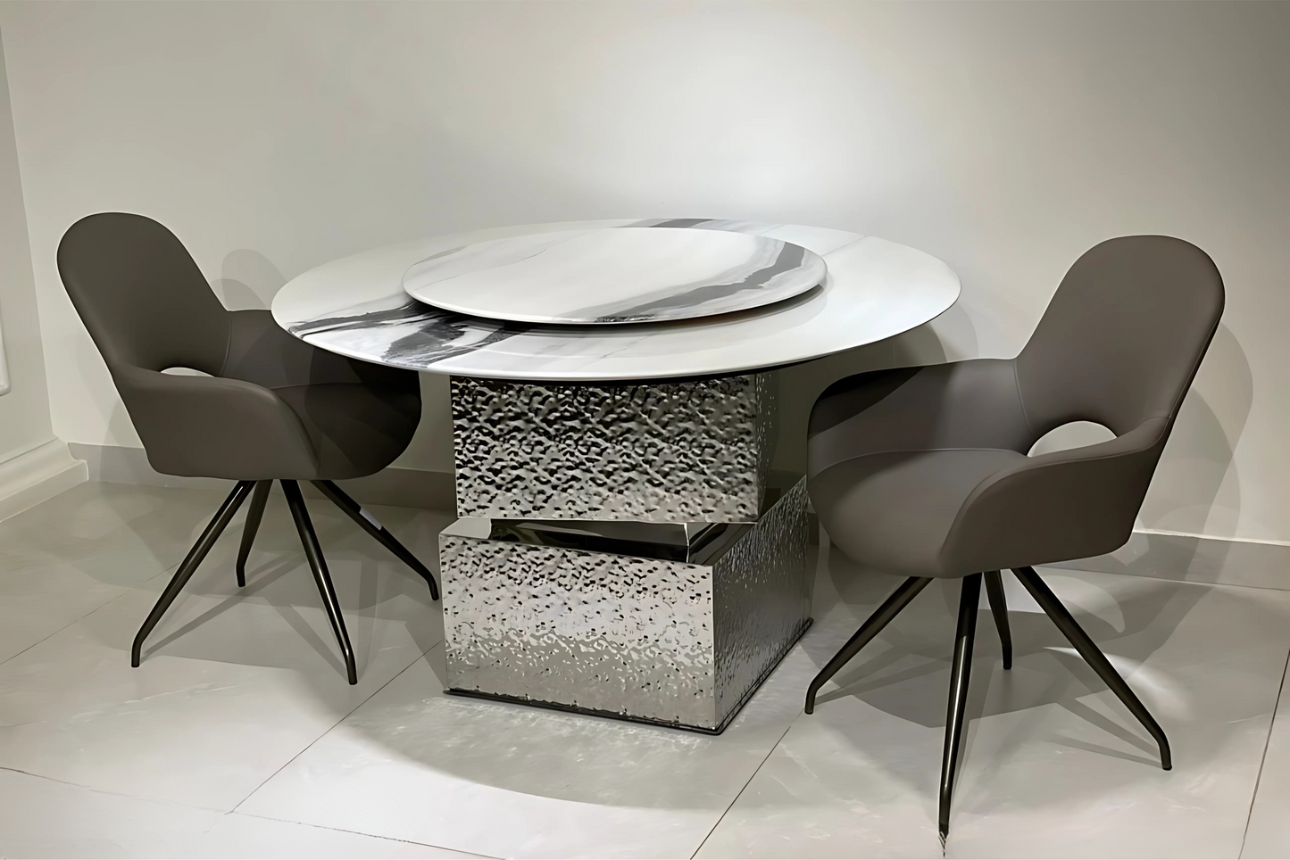 Round marble-look dining table with Lazy Susan and hammered chrome base, paired with taupe swivel dining chairs