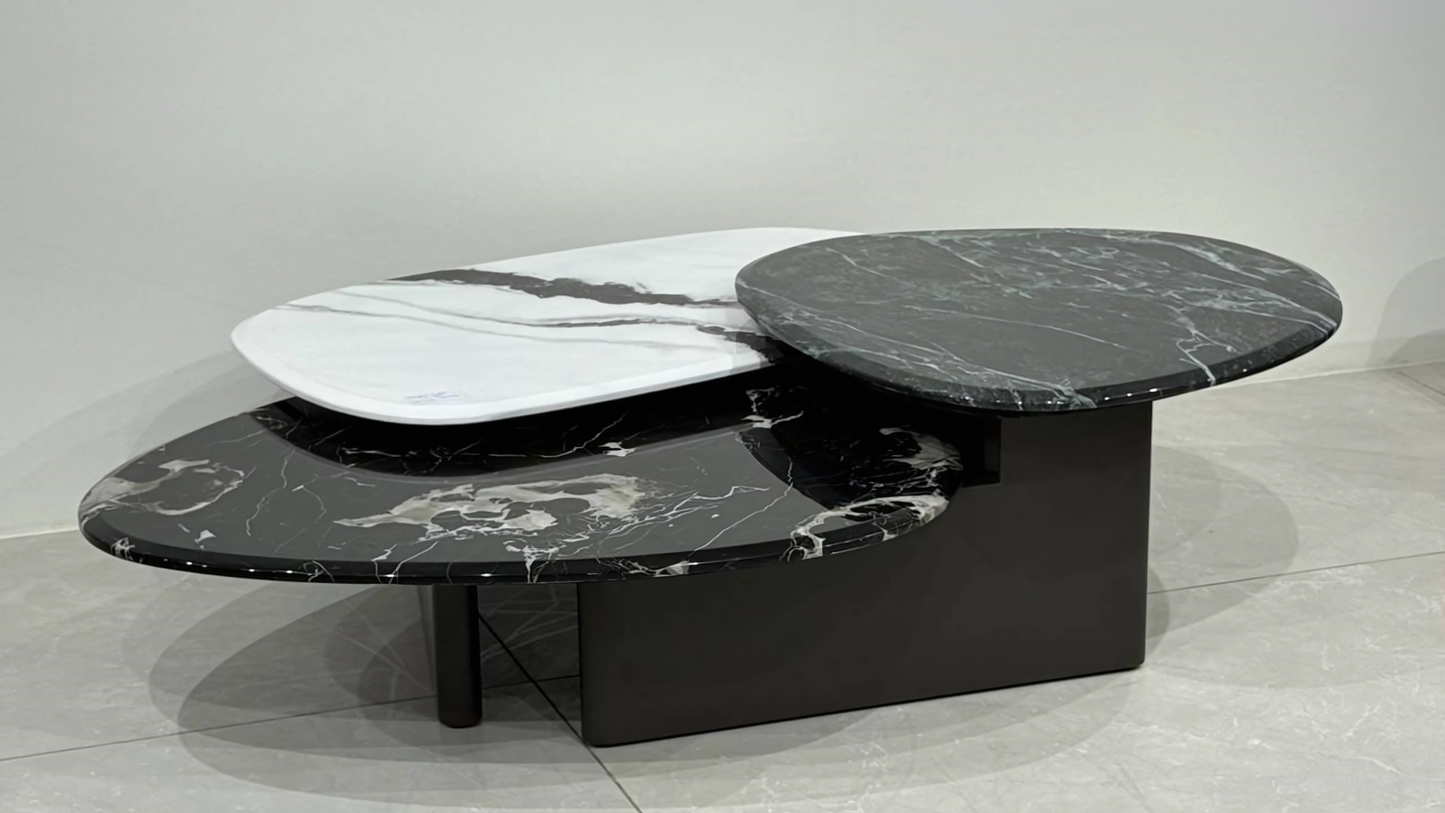 Three-tiered marble center coffee table in black, white, and green with sculptural curved design and layered stone tops