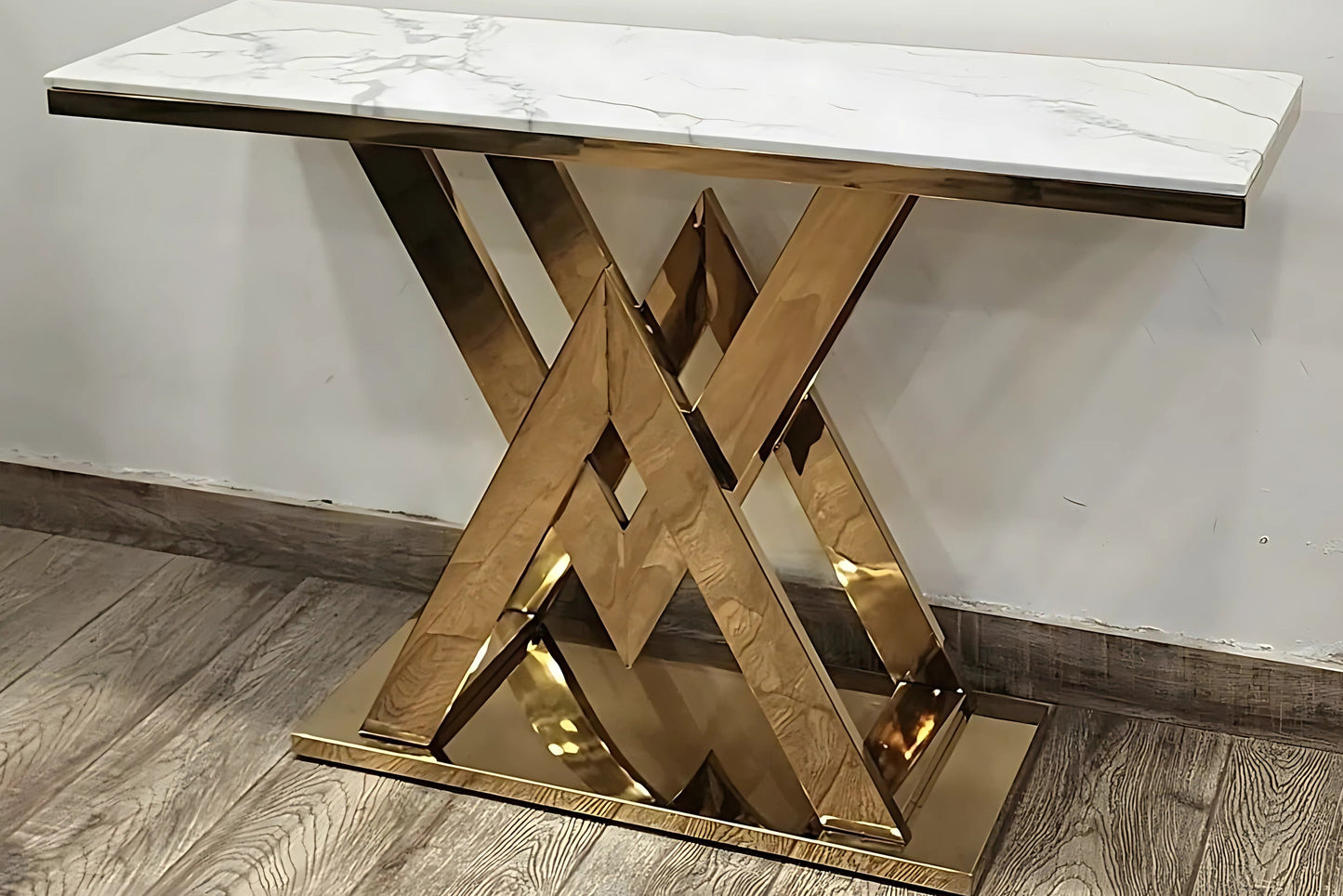 A black marble top console table with gold looped legs on a white background.