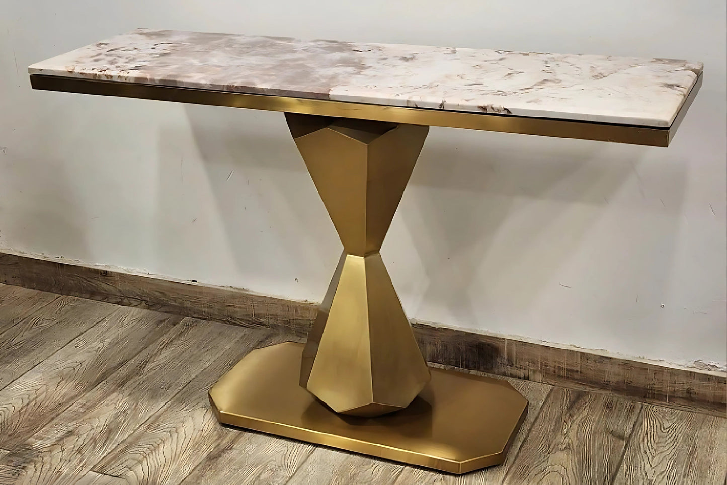 A rectangular black marble console table with gold looped legs placed on a wooden floor against a white background.