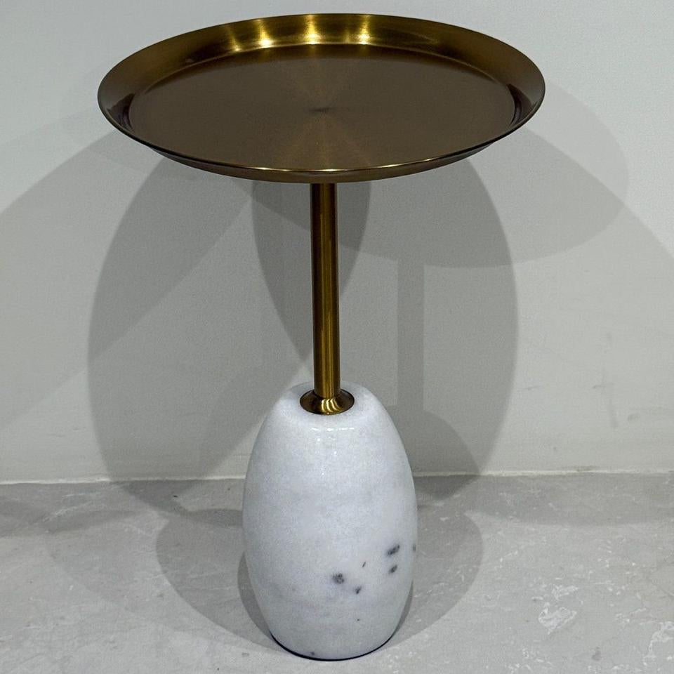 Side table with brass top and marble base on a gray background