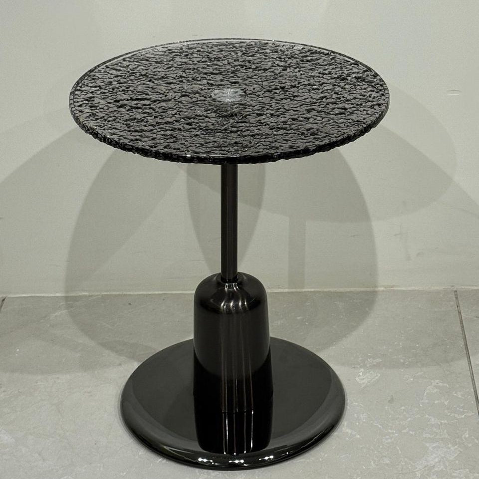 Black side table with textured top on a white background