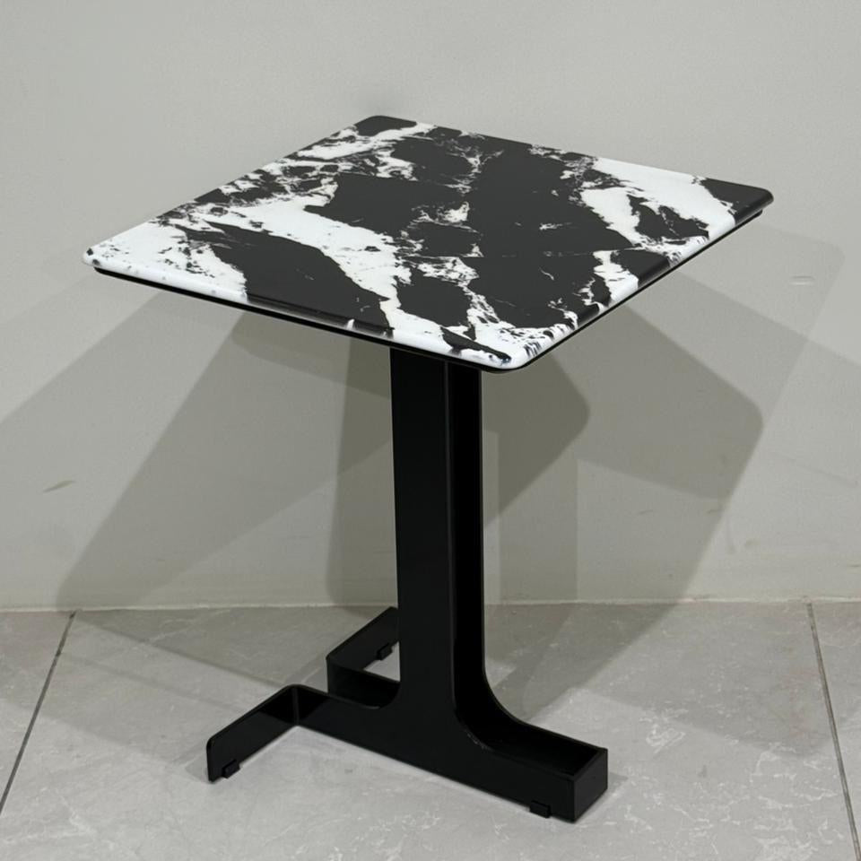 Side table with black and white marble top on a gray floor.