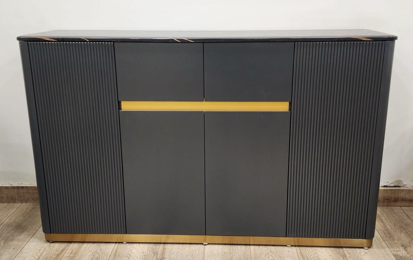 Gray sideboard with gold accents on a wooden floor against a white wall