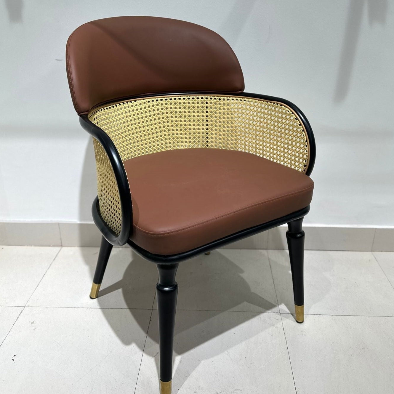 Luxury cane-back dining chair with brown leatherette seat and gold-tipped black legs