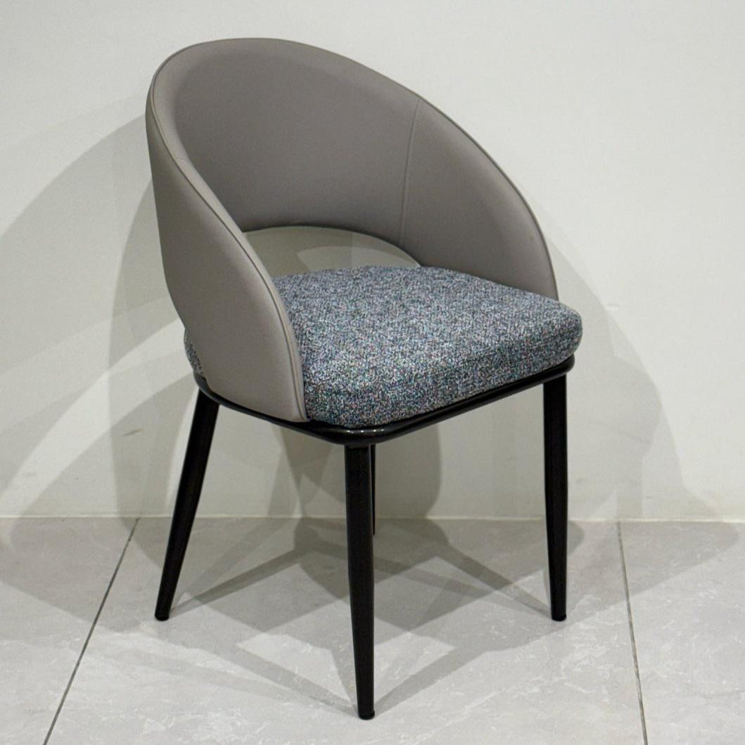 Chair with gray cushioned backrest and black legs on a light gray floor.