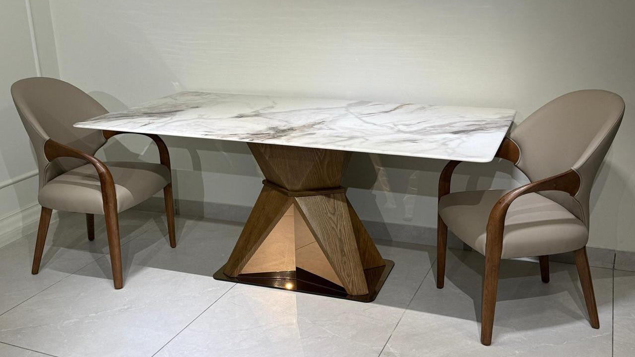 Dining table set with marble top and wooden legs, accompanied by chairs on a tiled floor.