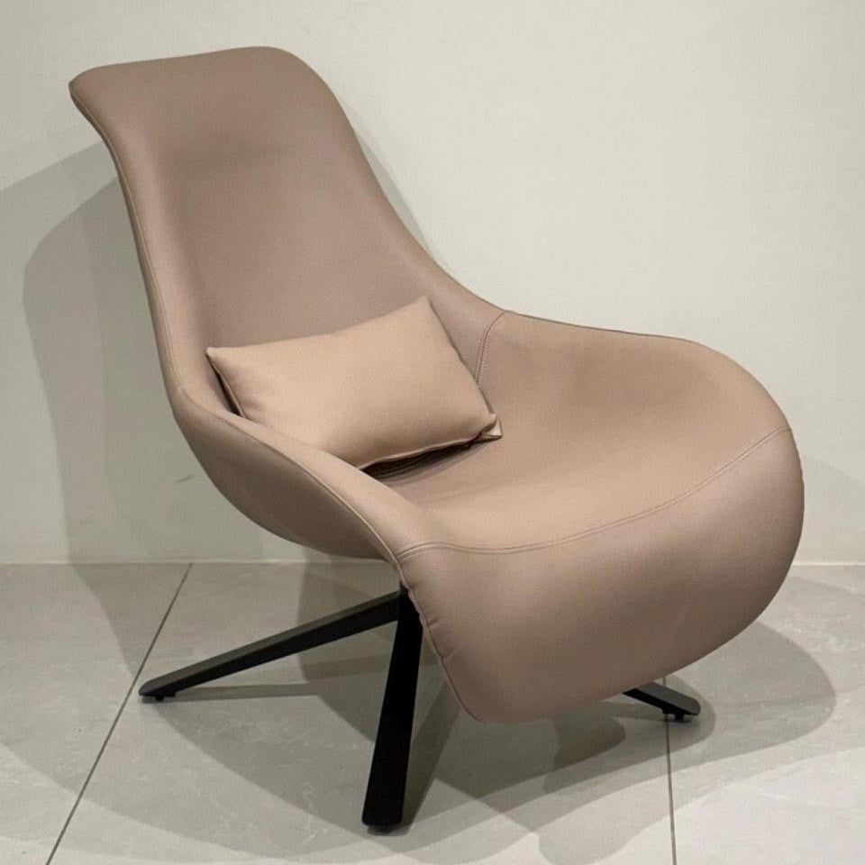Beige leisure chair with a pillow on a light gray floor and white wall