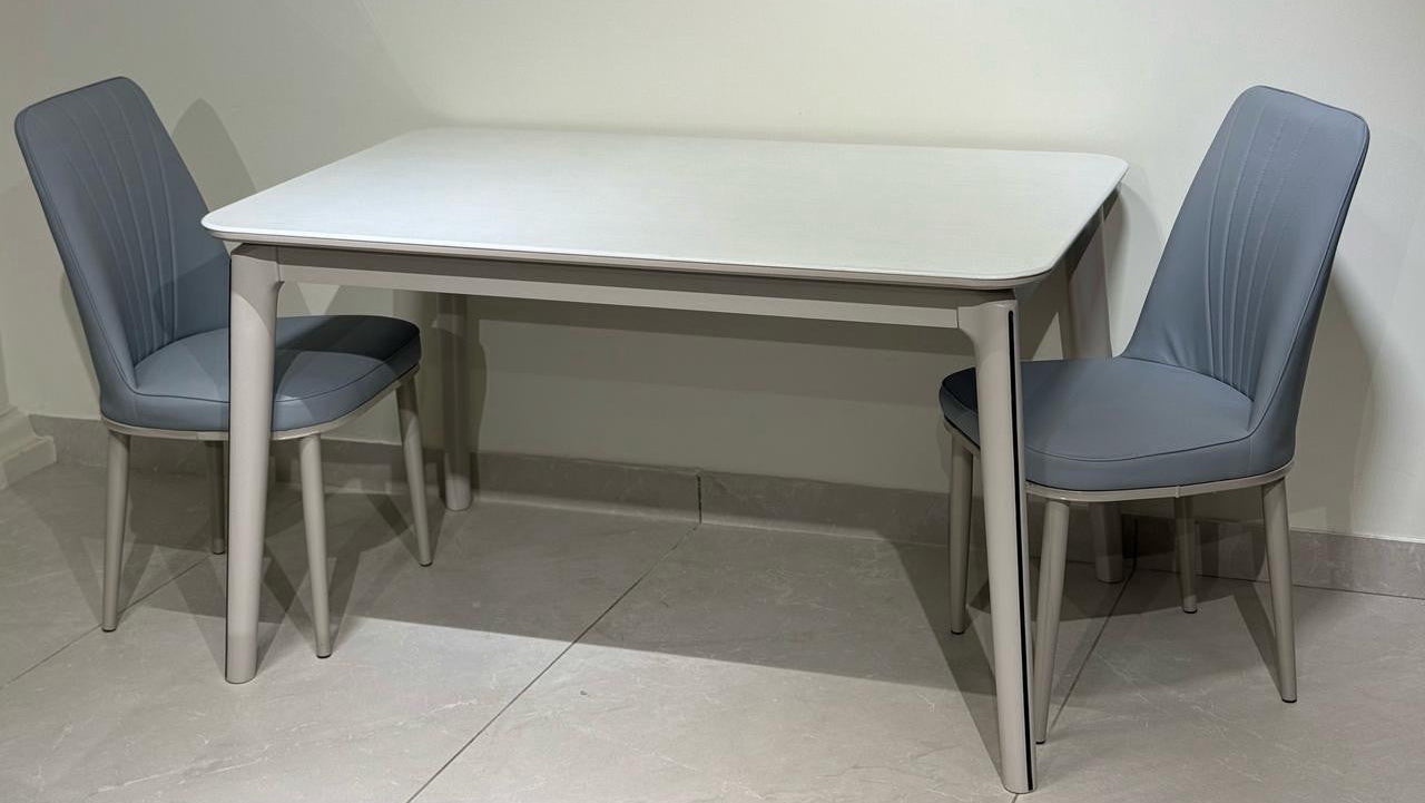 Dining table set with two chairs on a tiled floor against a white wall.