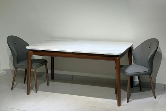 A rectangular dining table with a white tabletop and brown wooden legs, accompanied by two gray upholstered chairs.