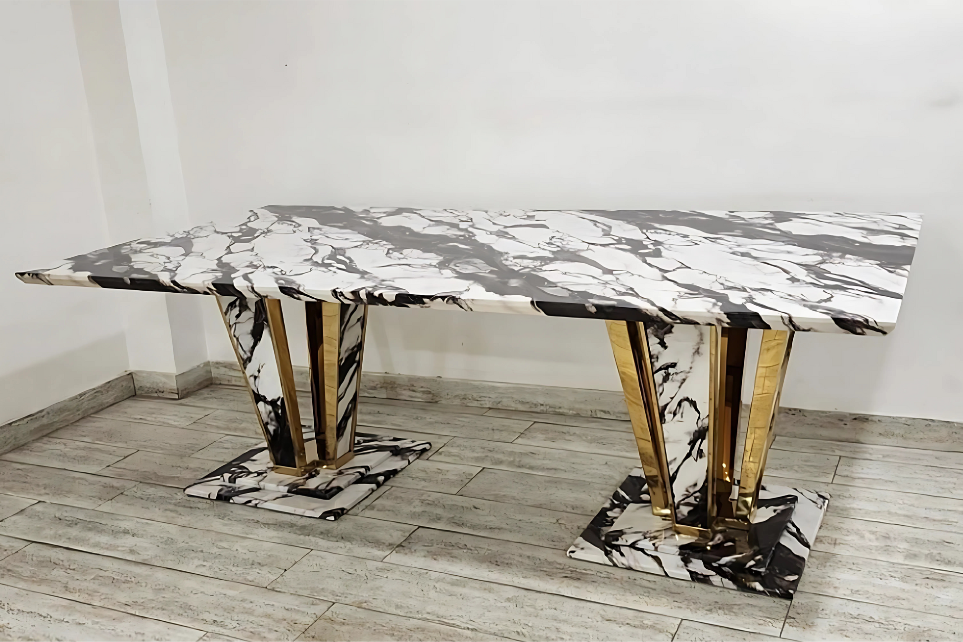 Bold luxury dining table with black and white marble finish and sculptural gold prism twin base