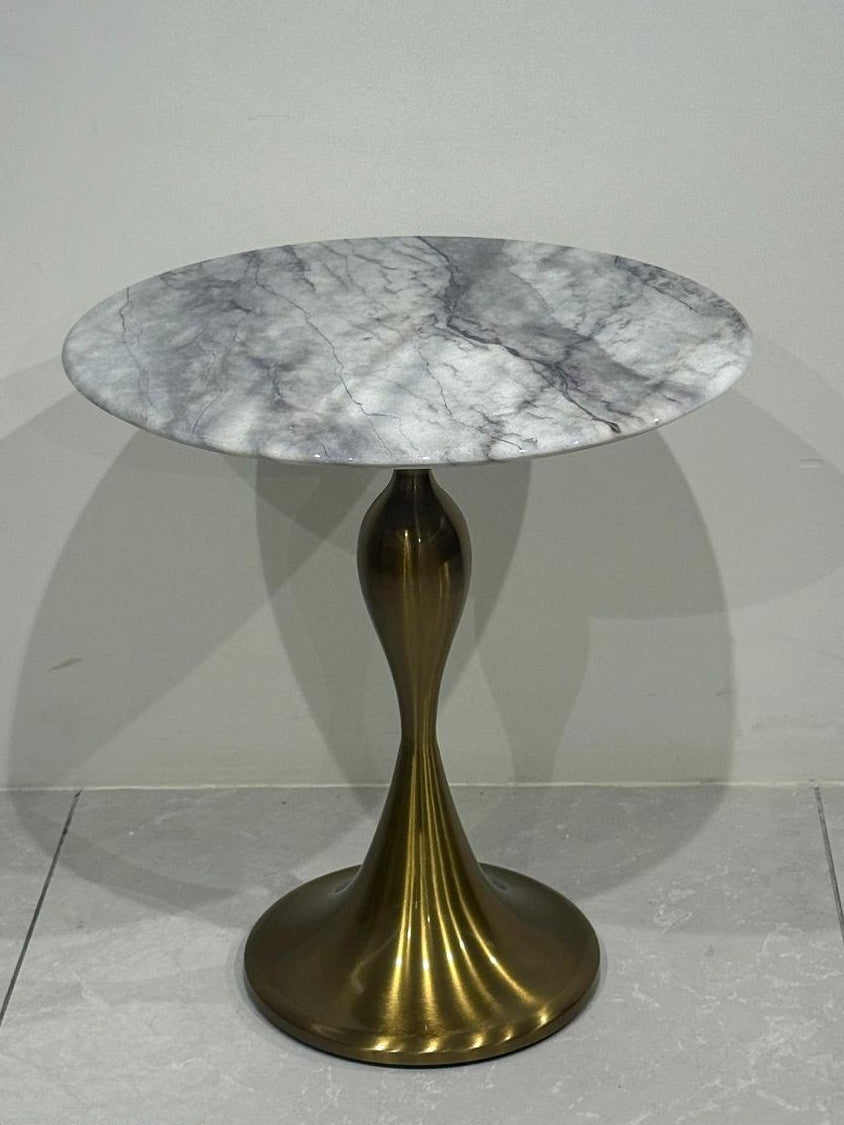 Round marble Side table with a bronze base on a light gray floor.