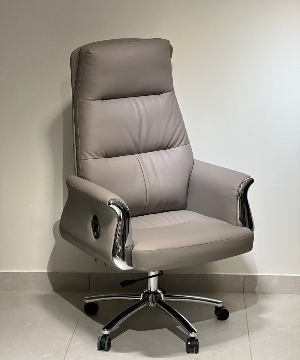 Grey high-back executive office revolving chair with chrome armrests and cushioned seat