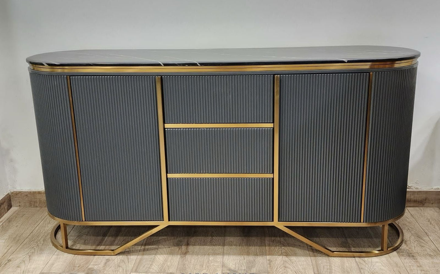 Modern sideboard with gold accents on a wooden floor against a white wall