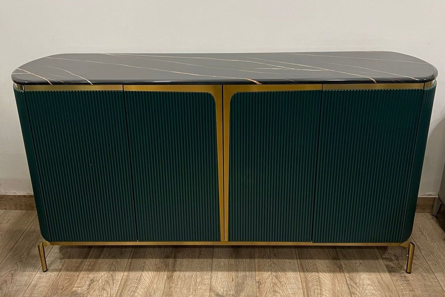 Green cabinet with marble top on a wooden floor.