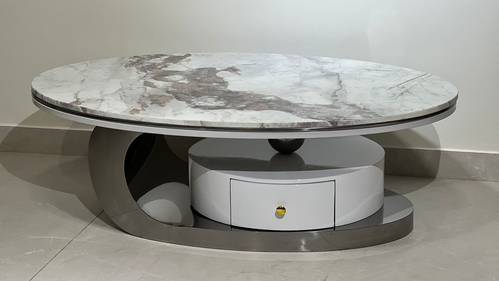 Round marble coffee table with a drawer on a light gray floor.