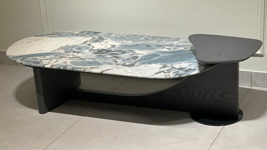 Oval marble-effect coffee table with asymmetrical sculptural black wood base and artistic wing extension