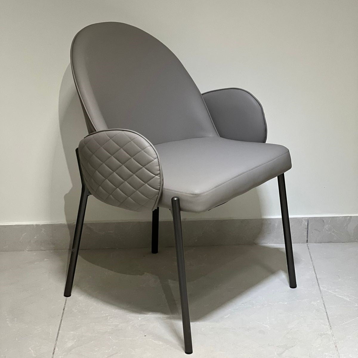 Dark grey luxury chair with quilted arm detailing and sleek black legs