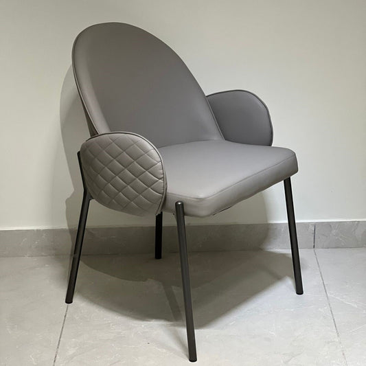Dark grey luxury chair with quilted arm detailing and sleek black legs