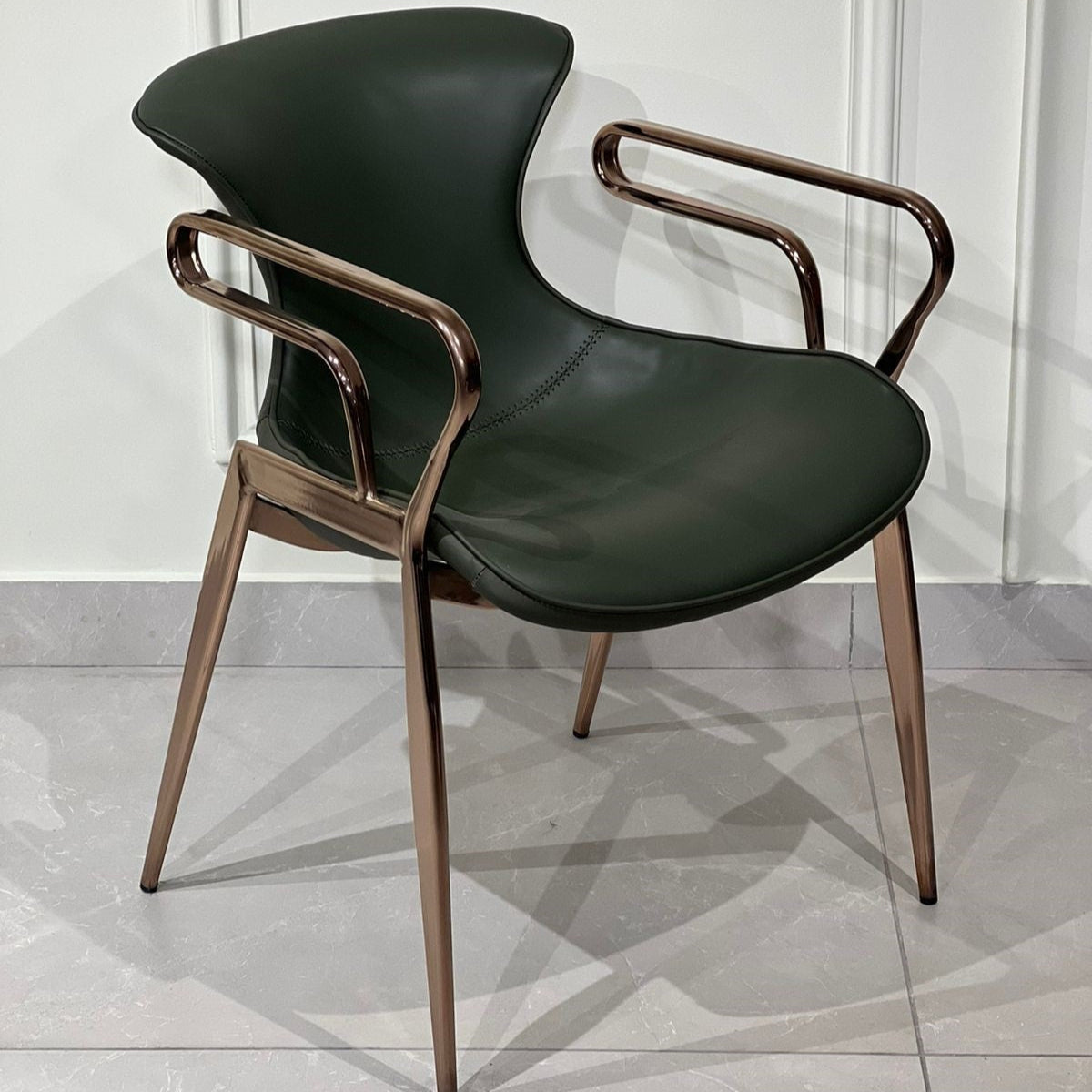Luxury green upholstered chair with sculptural rose-gold frame and modern curved design