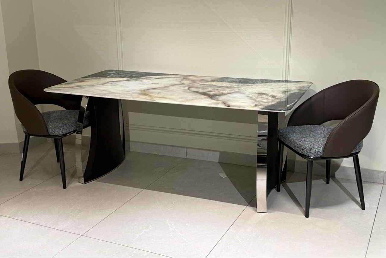 Dining table set with marble-patterned table and dark brown chairs in a neutral setting.