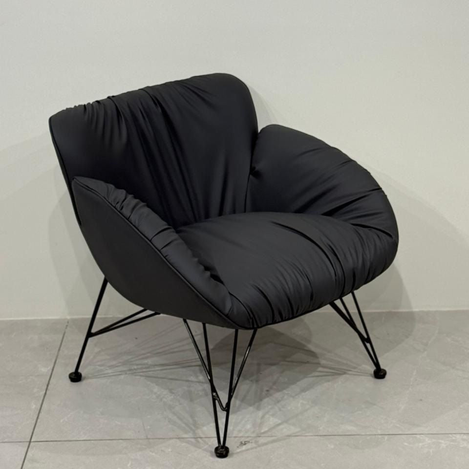 Dark grey leisure chair on a light gray floor with a white wall background
