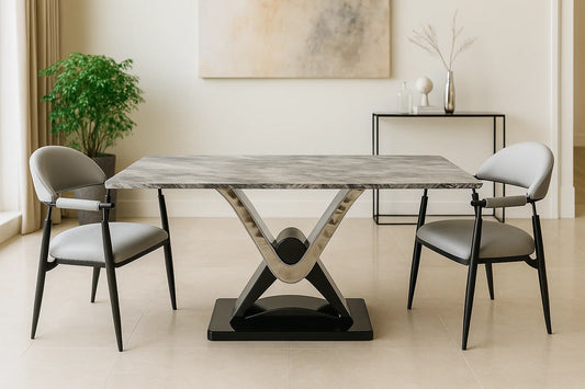 Grey marble dining table with V-shaped steel base and upholstered grey chairs in a modern luxury setting