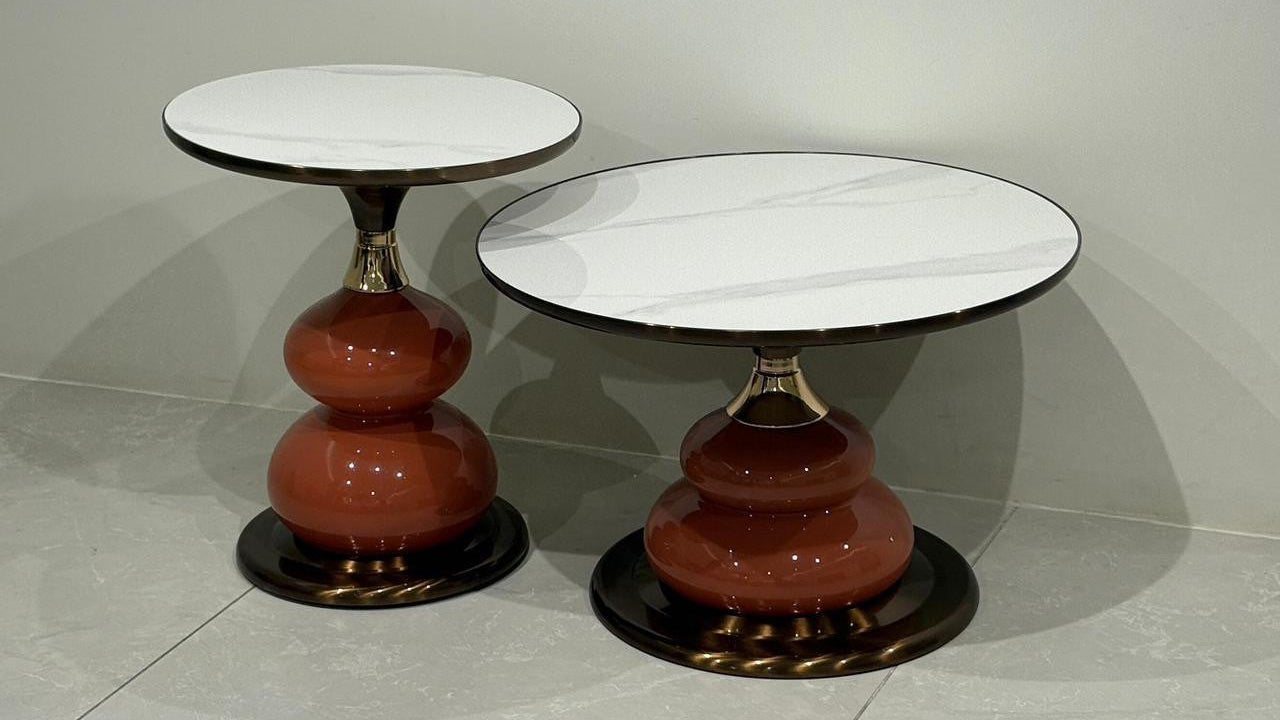 Two center tables with marble top and red cylindrical base on a gray floor.