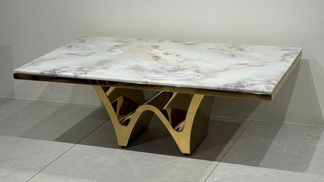 Gold center table with marble-like top on a gray floor 