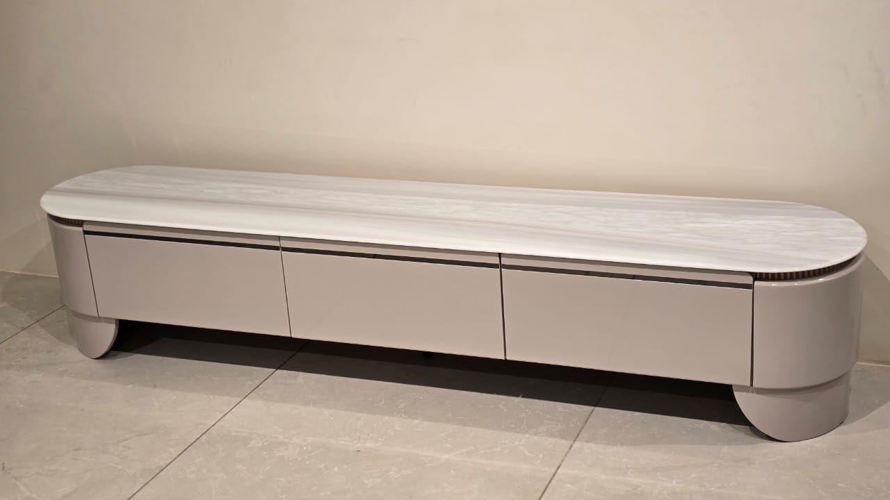 Long, narrow TV stand with a marble-like finish on a beige floor.
