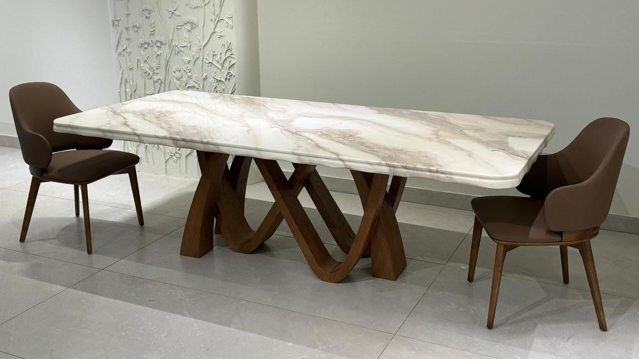 Dining table with marble-like surface and wooden legs in a room setting.