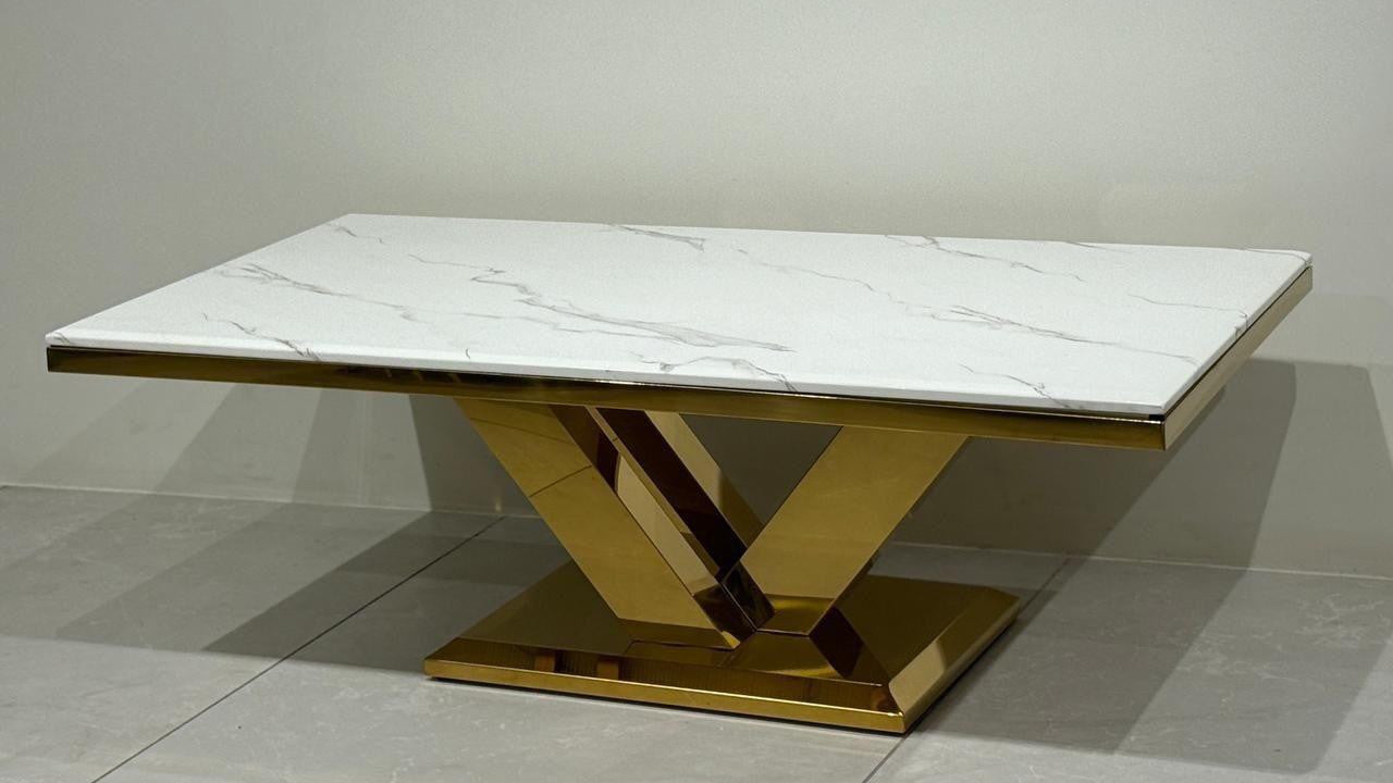 Center table with marble top and gold base on a gray floor. 