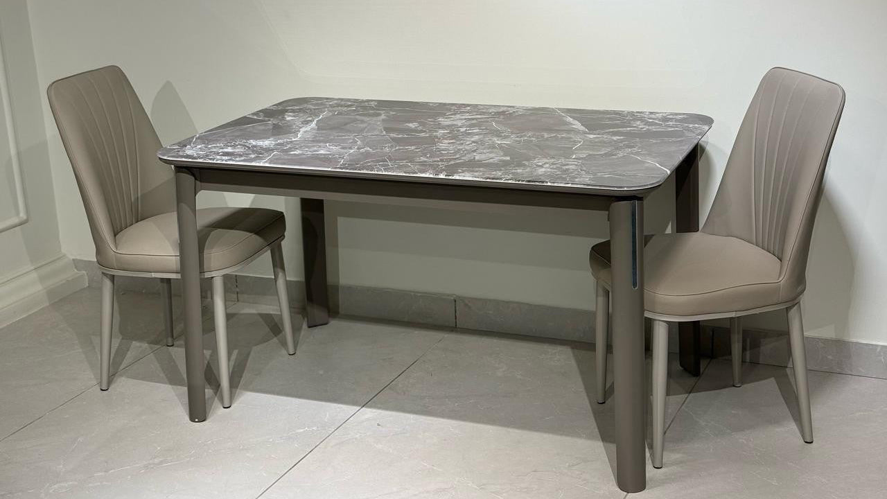 Dining table set with marble top and beige chairs on a light gray floor.