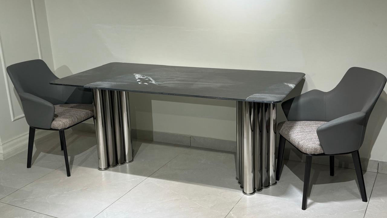 Dining table set with two chairs on a tiled floor against a white wall.