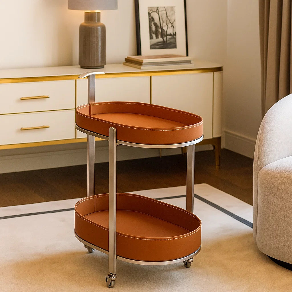 Two-tiered round serving cart with brown leather trays in a stylish room.
