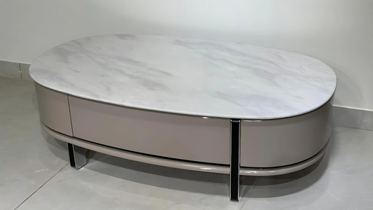 Oval marble-top luxury center table with glossy beige base and sleek modern design.